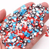 A pile of polymer clay slices in red, white, and blue colors with black designs is held in a hand.