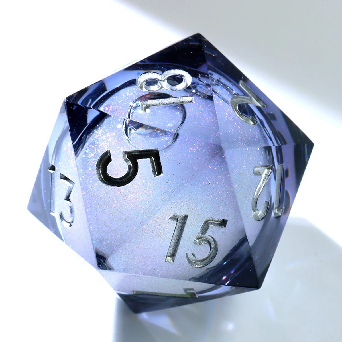 A handmade resin D20 die with a large blue and purple liquid swirl, viewed at an angle.