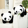 A white and black bamboo panda plush stuffed animal sitting on a light-colored sofa.