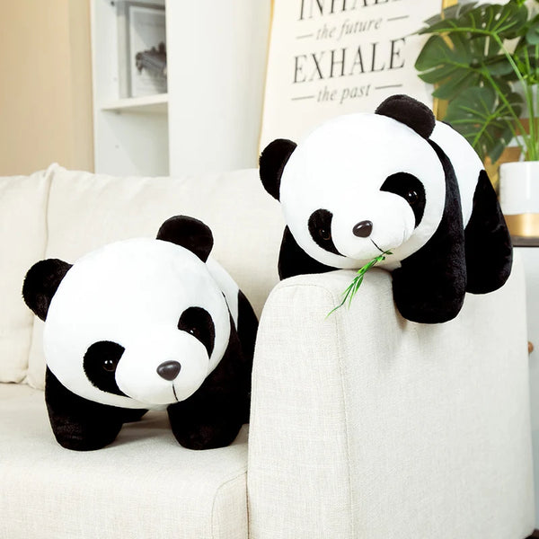 Un ours panda en bambou blanc et noir, peluche, assis sur un canapé clair.
