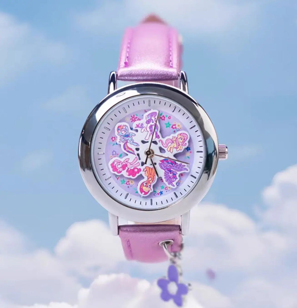 A pink My Little Pony Magic Sweetheart blind box watch with a purple strap is shown against a bright blue sky and white cloud