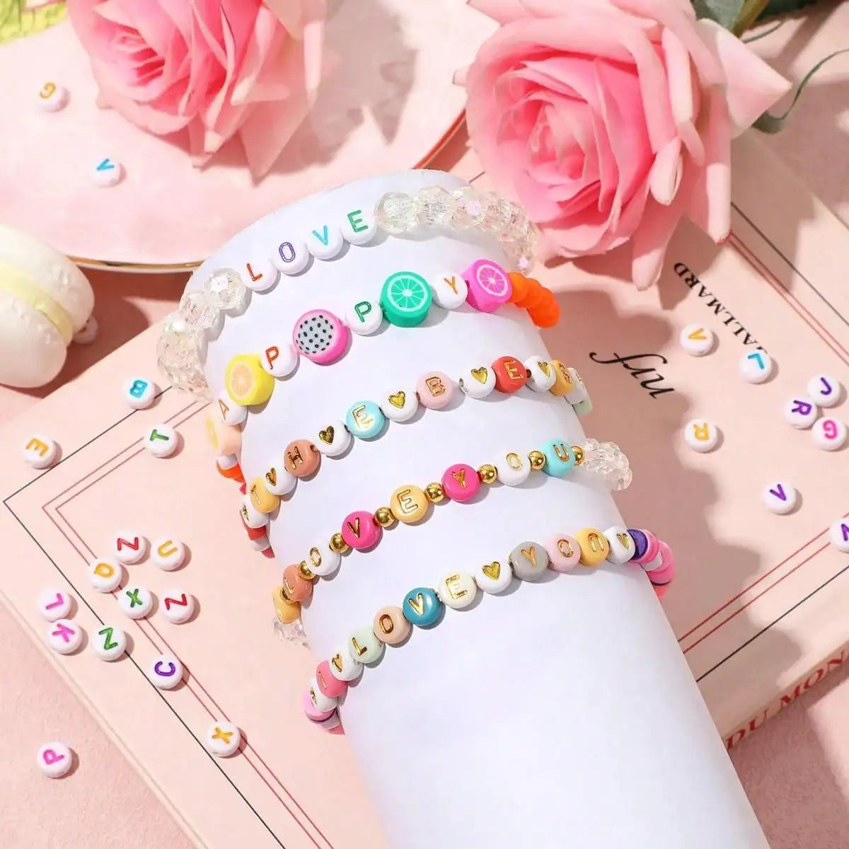 A stack of white acrylic beads with various letters and numbers in pink, green, and orange colors for jewelry making