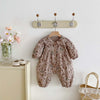 A floral doll collar baby girl long sleeve jumpsuit hanging on a wall rack.