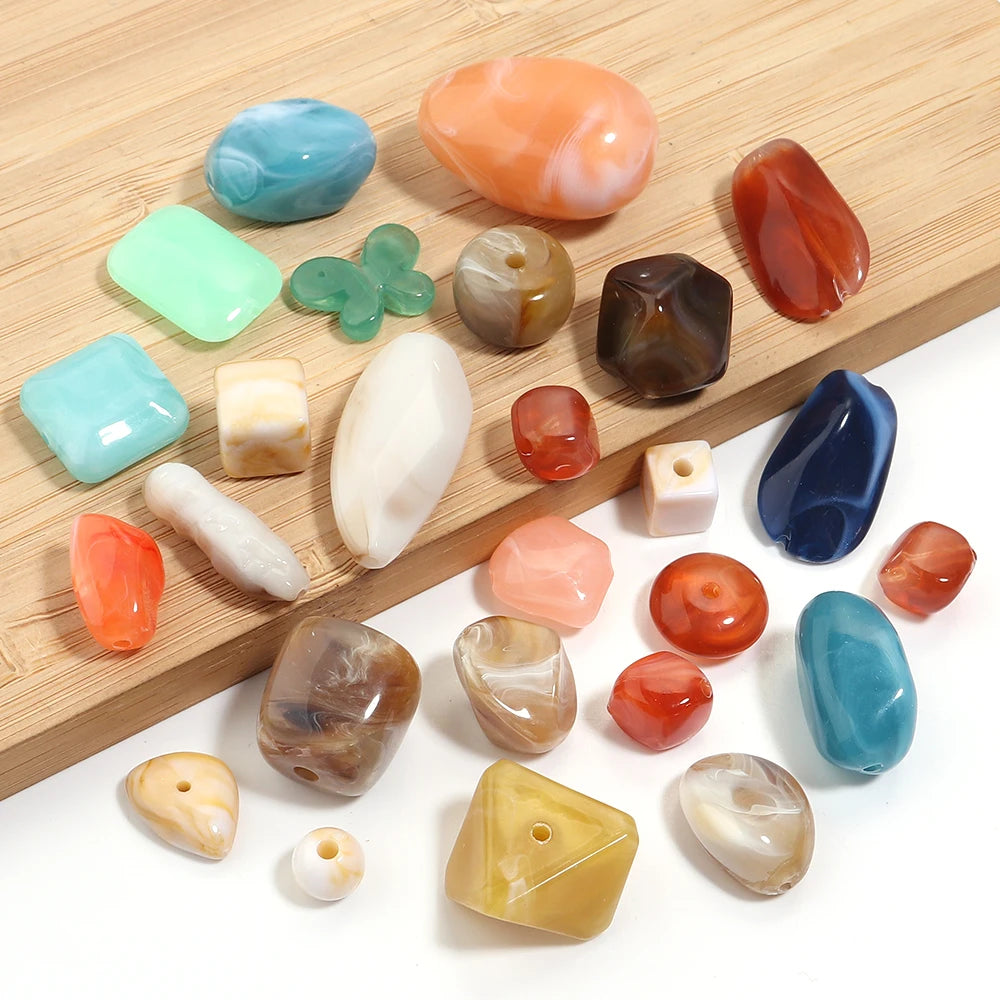 A collection of colorful acrylic beads in various shapes and translucent colors arranged on a wooden surface.