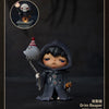 A dark-skinned collectible figure of a character wearing a hooded cloak and holding a chain, with a smaller monster figure vi