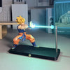 A figurine of Son Goku performing a Kamehameha pose, illuminated by a bright blue light, displayed on a black desk lamp base.