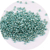 A pile of small, metallic, round glass beads in a teal or greenish-blue color.