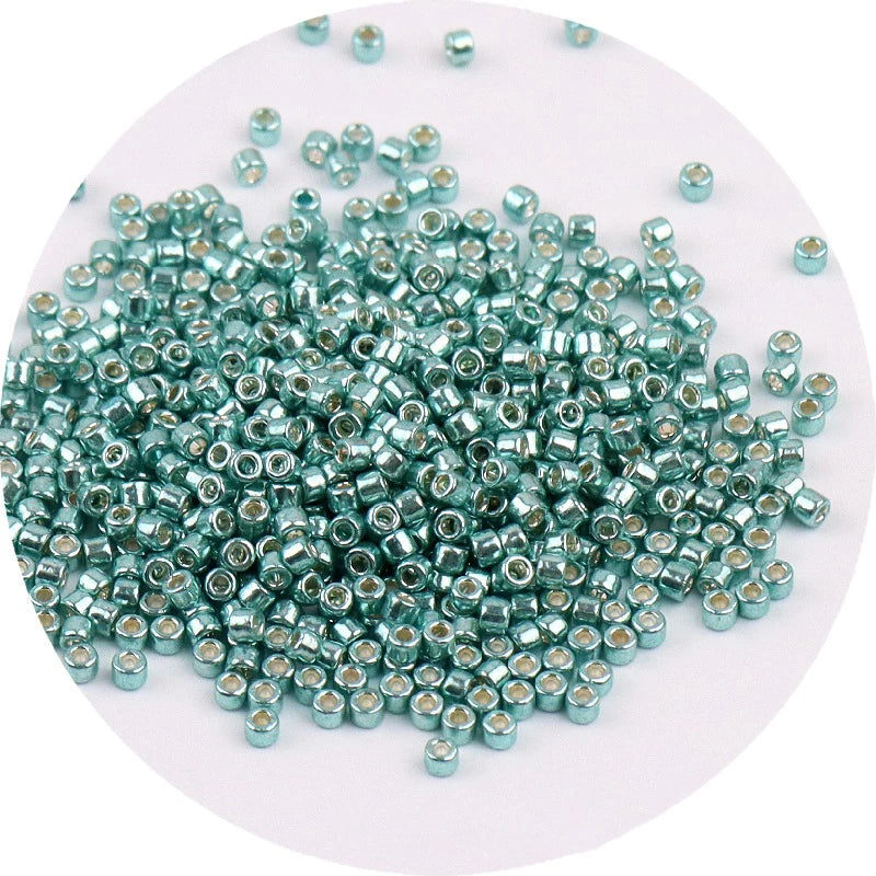 A pile of small, metallic, round glass beads in a teal or greenish-blue color.