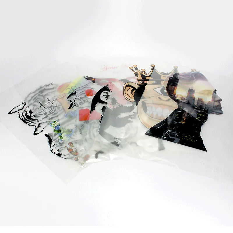 A sheet of artistic DTF transfer film featuring layered, stylized human faces and abstract designs.