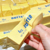 A hand holds a yellow butter fidget toy with the label 4oz salted butter net wt 113