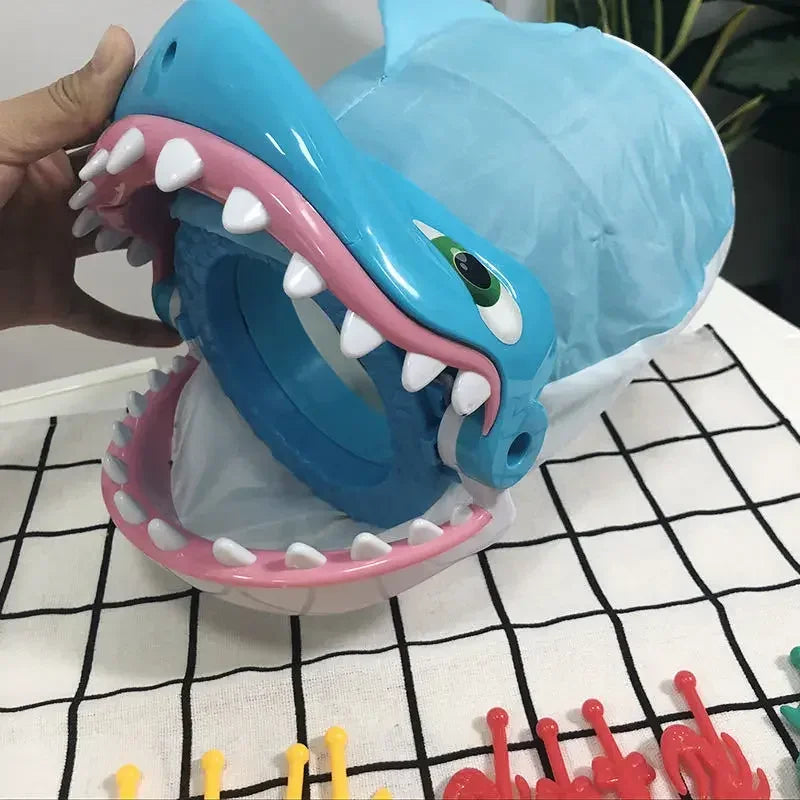 A blue shark-themed prank board game featuring a large plastic mouth and teeth, displayed on a white surface.