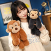 A woman is holding a brown plush monkey soft toy and a gray plush monkey soft toy.