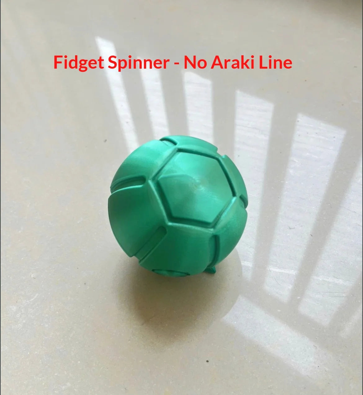 A teal fidget spinner toy is shown on a white surface with shadows cast across it.