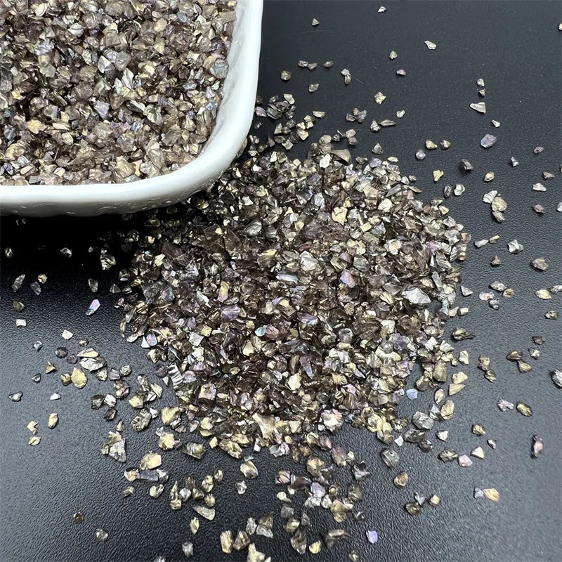 Crushed glass mix for resin and jewelry making scattered on a dark surface.