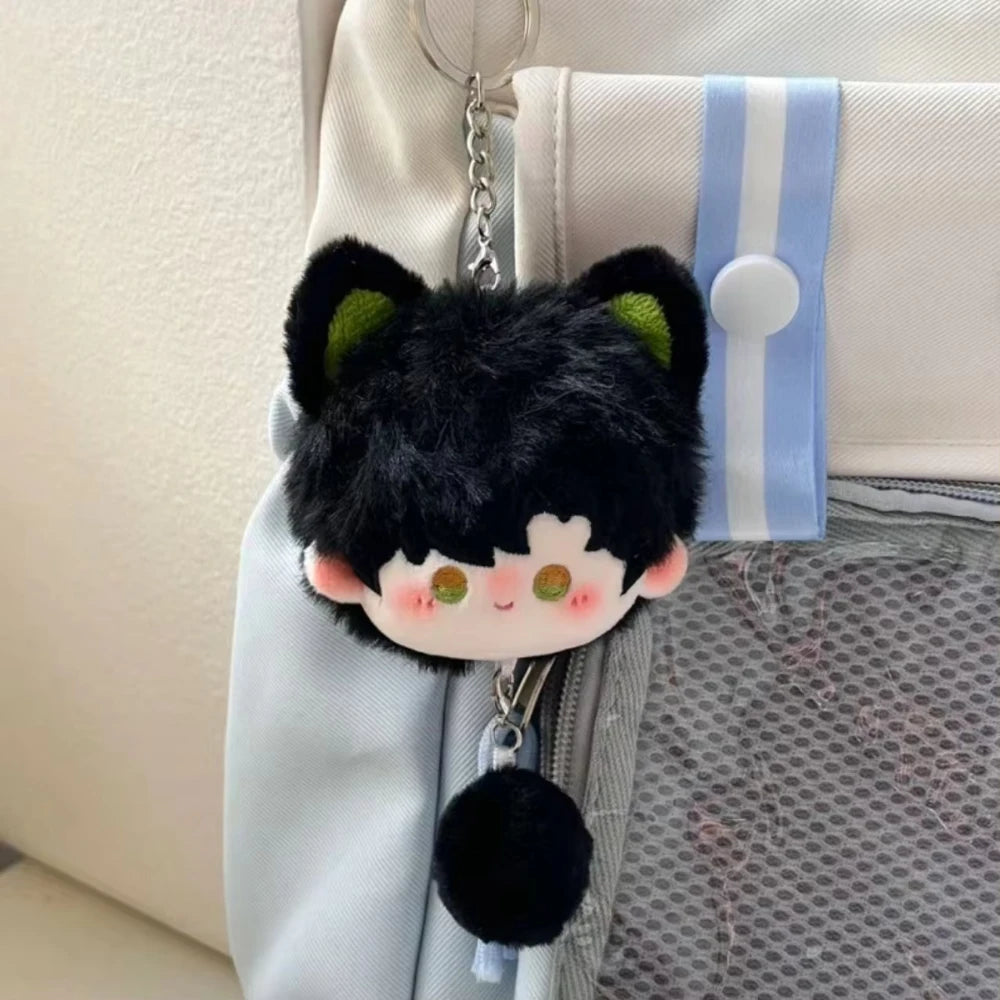 A black cat-shaped plush pendant keychain with green accents hanging from a light blue fabric strap.