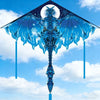 Un delta de cerf-volant bleu et argenté avec une figure angélique aux ailes glacées contre un ciel lumineux.