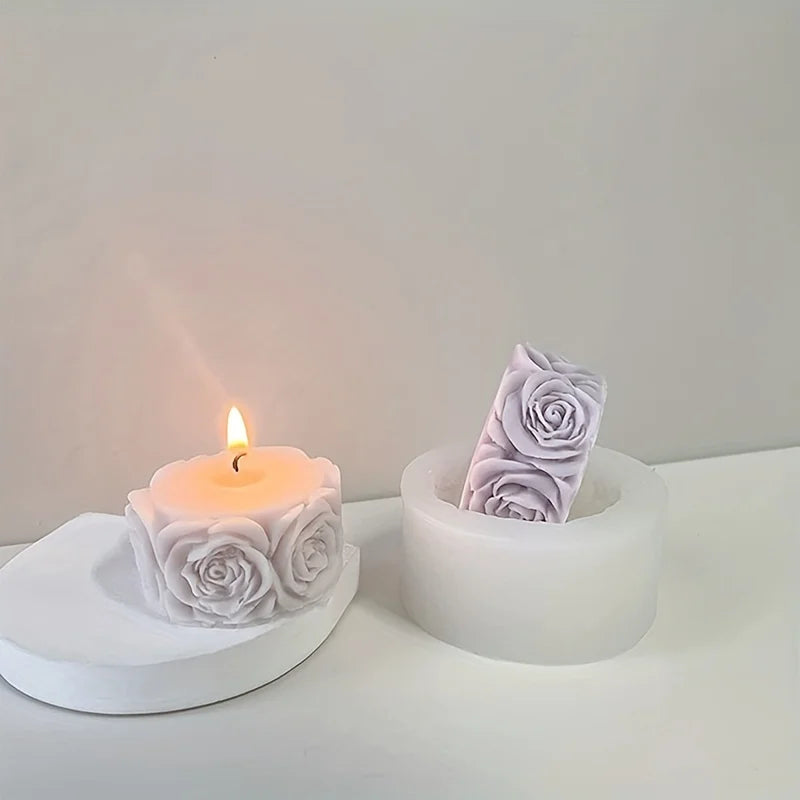 A white silicone rose candle mold sits next to a lit candle, casting a soft glow on a white surface.