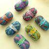 A collection of colorful Opal 4-ply sock yarn balls in various shades and patterns arranged on a light surface.