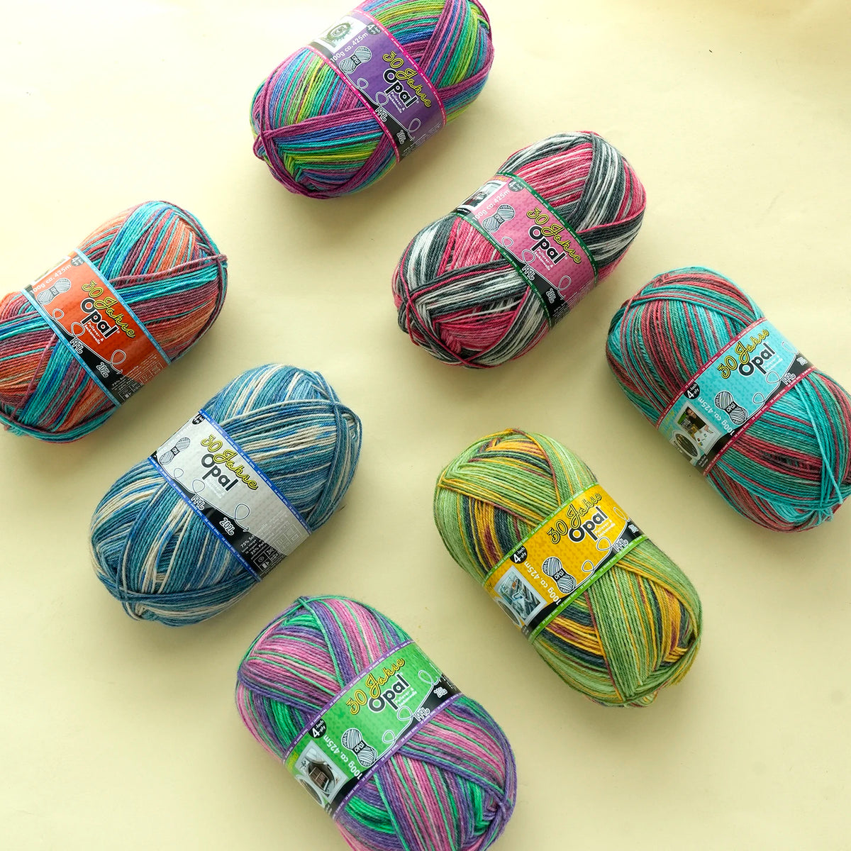 A collection of colorful Opal 4-ply sock yarn balls in various shades and patterns arranged on a light surface.
