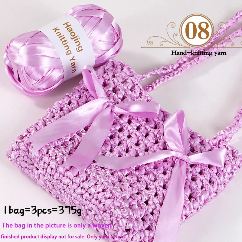 A pink knitted yarn ball and a finished woven bag made from the yarn, tied with satin ribbons.