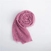 A dusty rose knit wrap folded into a rosette with small pearl embellishments.