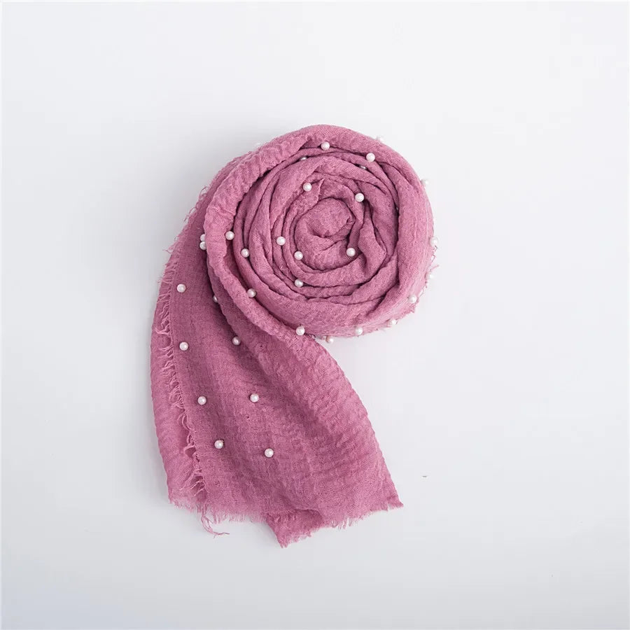 A dusty rose knit wrap folded into a rosette with small pearl embellishments.