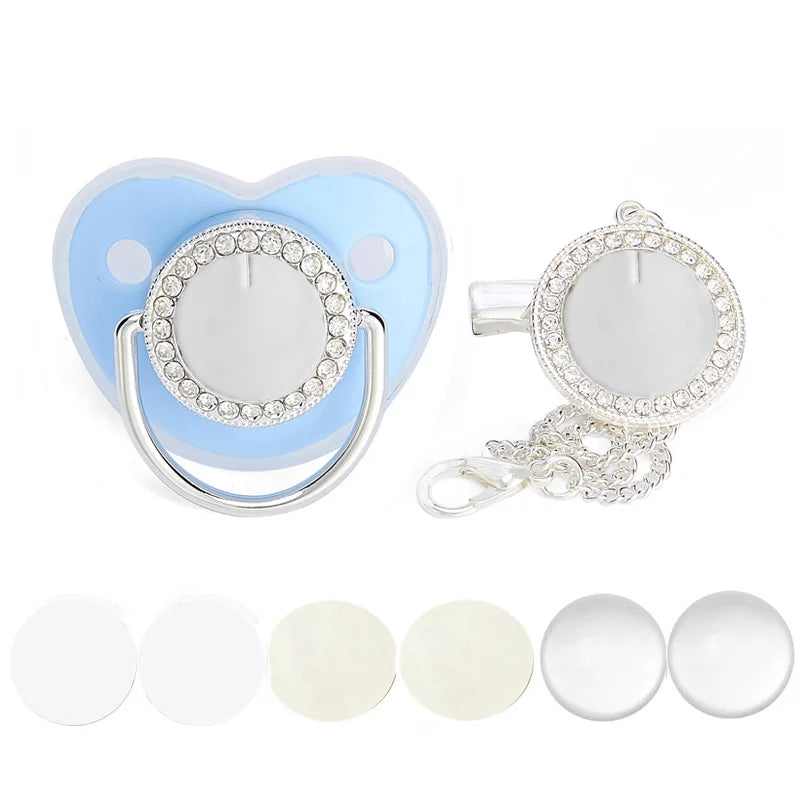 A set of baby pacifiers and clips featuring a light blue heart shape with rhinestone accents and various sized silicone tips.