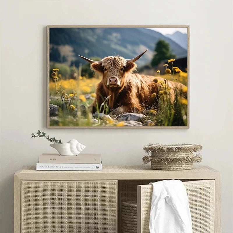 A painting of a brown Scottish Highland cow with horns in a field, displayed in a wooden frame.