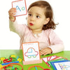 A young child holds up a wooden stick and ring puzzle toy with letters A and c on it.