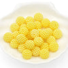 A pile of small, round, yellow acrylic pearl beads in a white dish.