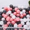 A white and pink ball pit filled with numerous colorful play balls for games