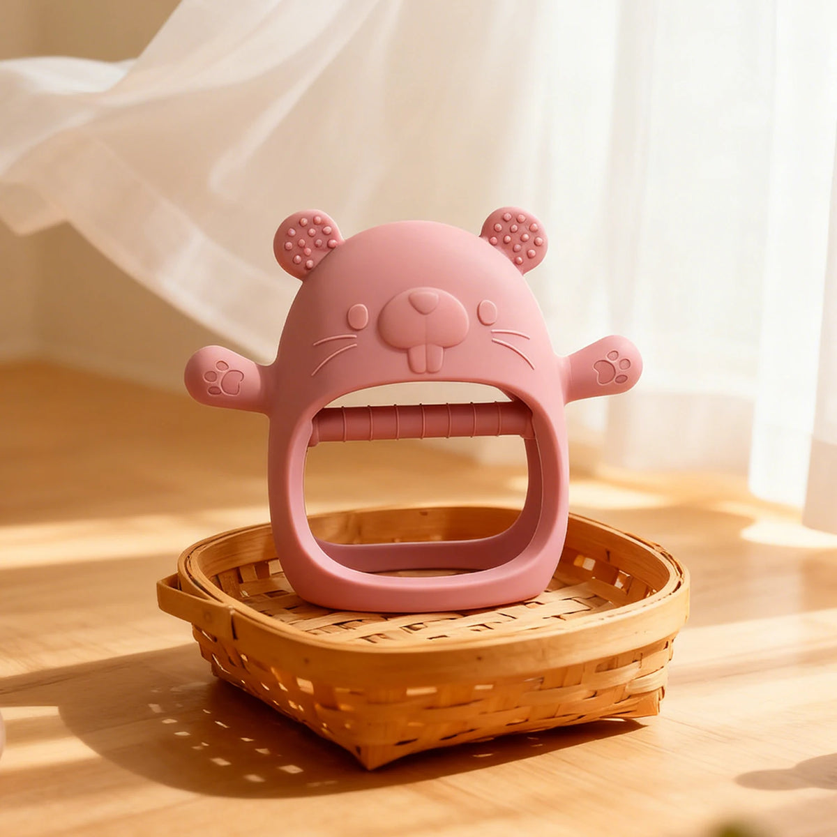 Pinkes Silikon-Stillmittchen in Katzenform auf einem Holzbrett.