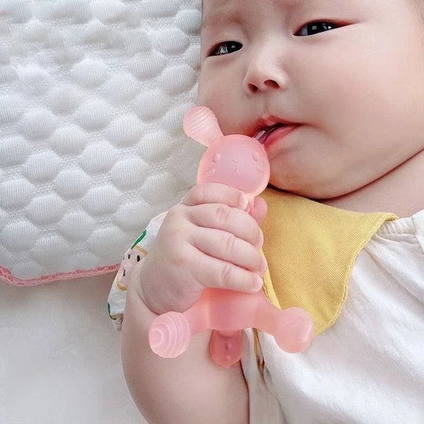 A baby is holding a pink silicone teether toy with a nipple on their lips.