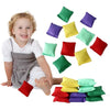 A child is smiling while holding a collection of ten colorful mini bean bags in various shades of green, yellow, and purple.