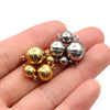 A hand holds a cluster of round stainless steel magnetic clasps in gold and silver finishes.