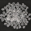 A pile of clear, faceted crystal bicone glass beads for jewelry making.