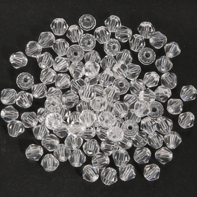 A pile of clear, faceted crystal bicone glass beads for jewelry making.