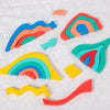 Colorful wooden rainbow blocks and puzzle pieces arranged on a white surface.