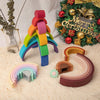A colorful silicone rainbow building block structure next to a festive Christmas wreath.
