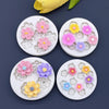 Six silicone molds shaped like various daisy flowers in pink, purple, and yellow for cake decorating