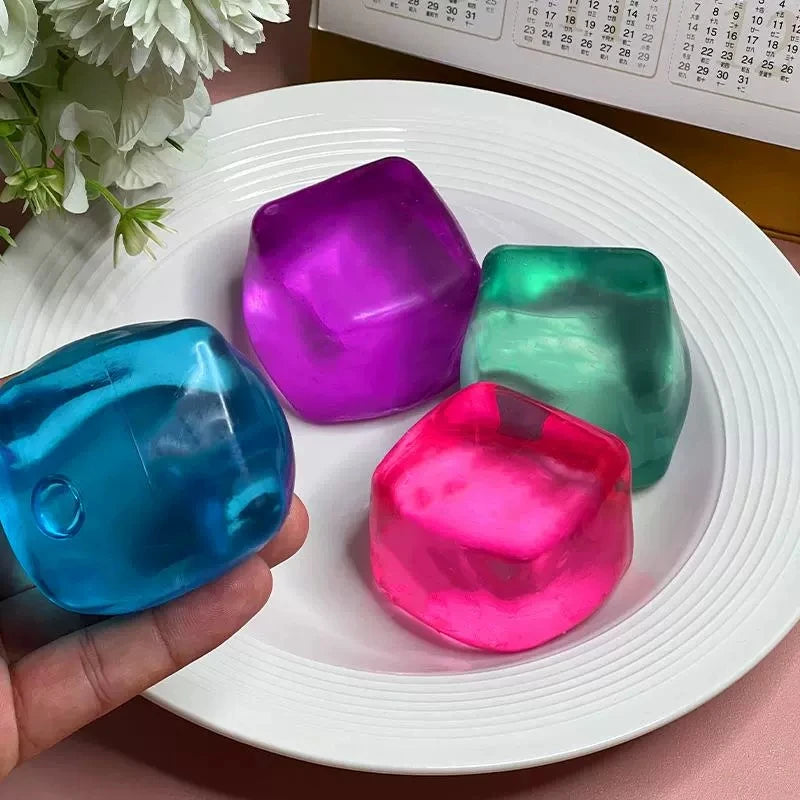A hand holds a vibrant pink ice cube sensory fidget toy on a white plate.