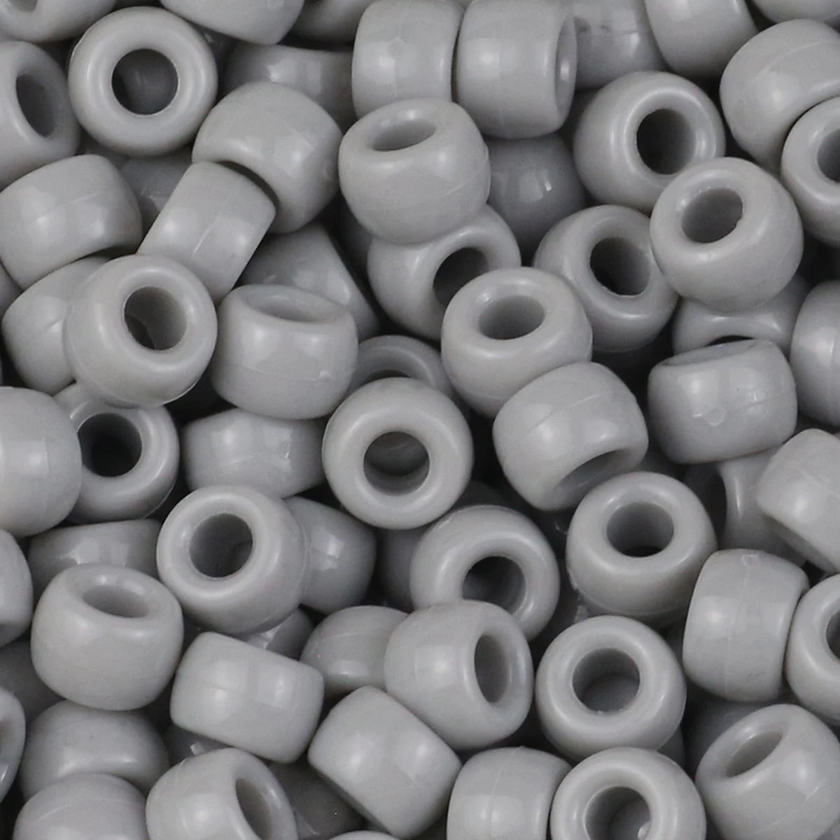 A close-up view of small, solid gray pony beads for jewelry making and craft projects.