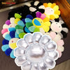 A large, silver-colored sunflower plush cushion with a cheerful design is shown on a dark surface.
