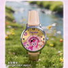 A pink and purple My Little Pony themed watch with a leather strap set in a natural outdoor background.