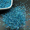 A pile of crushed blue crystal glass mix scattered on a dark surface.