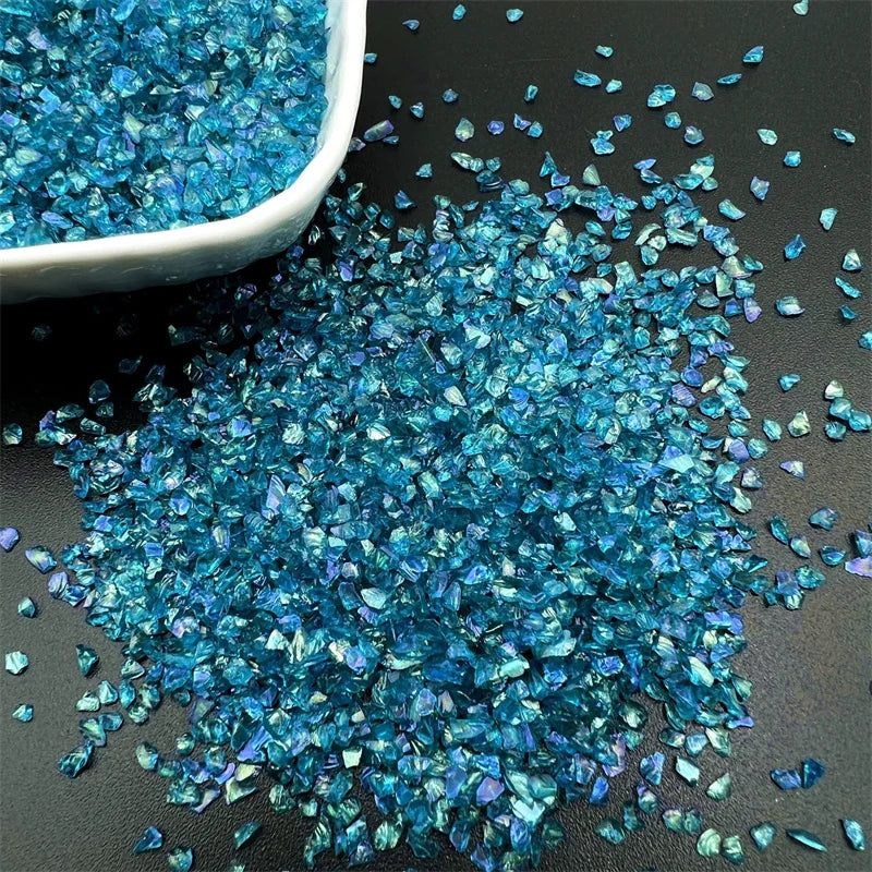 A pile of crushed blue crystal glass mix scattered on a dark surface.