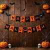 A dark wooden background decorated with an orange and black Halloween paper flag banner featuring witch, bat, and pumpkin sha