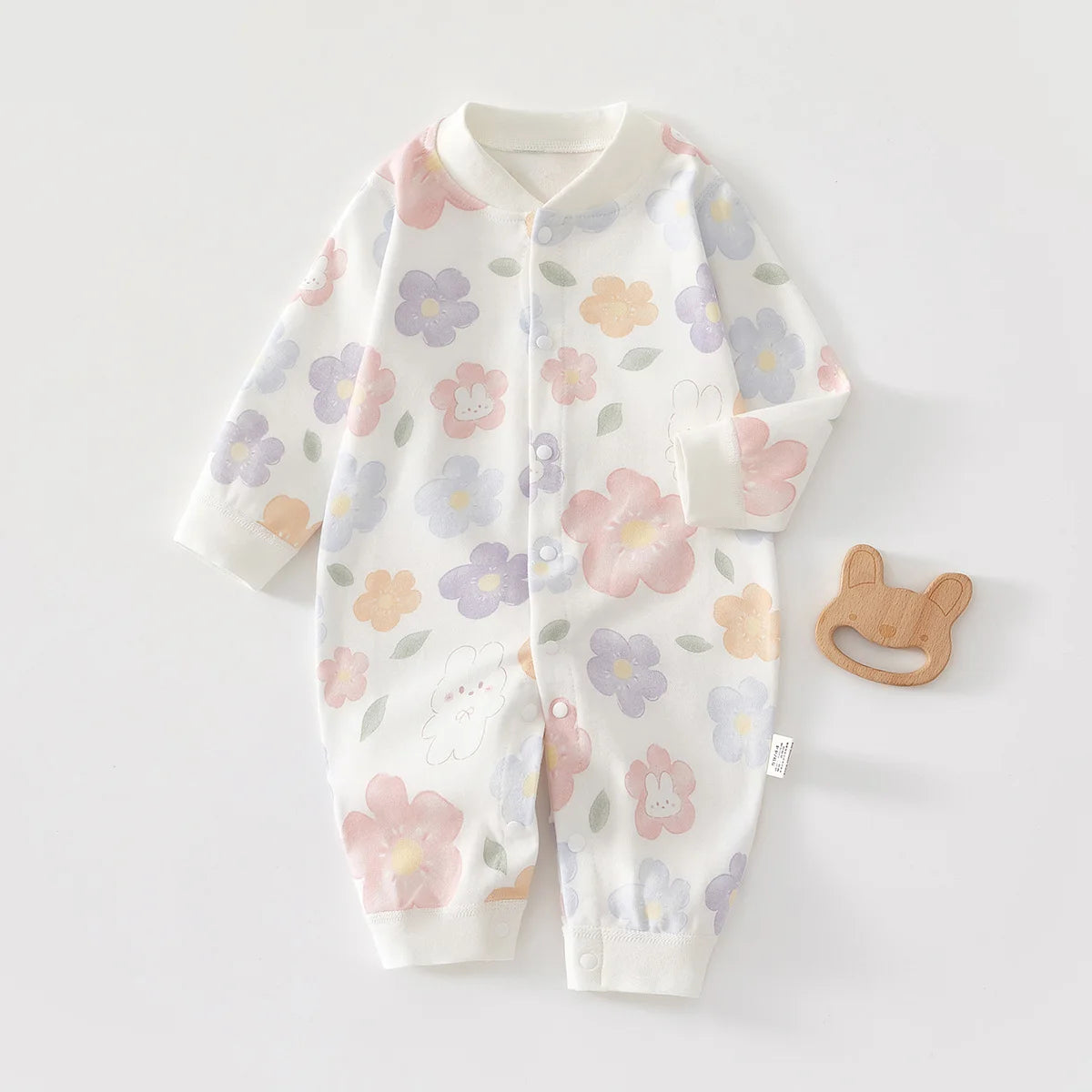 A white cotton long sleeve baby romper featuring a floral print of pink, purple, and orange flowers.