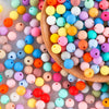 A wooden spoon holds a variety of colorful silicone beads in assorted sizes for DIY jewelry making