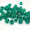 A pile of faceted green bicone crystal glass beads for jewelry making.